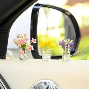 Macro view of mini car dashboard glass vases with colorful artificial flowers for decoration.