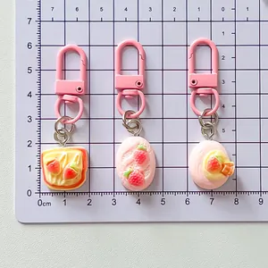 Detailed view of three simulation strawberry food keychains on a size reference grid