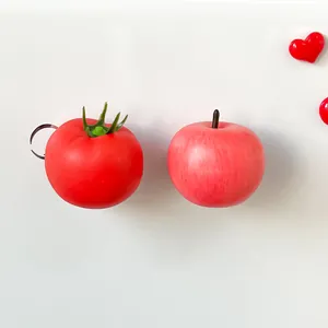 Detailed close-up view of realistic artificial tomato and red apple refrigerator magnets