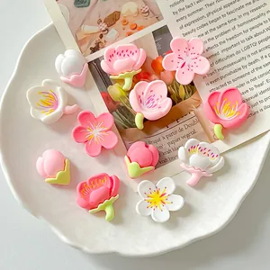 Detailed view of various pink and white resin cherry blossom charms for DIY crafts