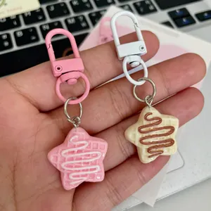 Gros plan de porte-clés gaufre en étoile en résine rose et crème avec mousquetons.