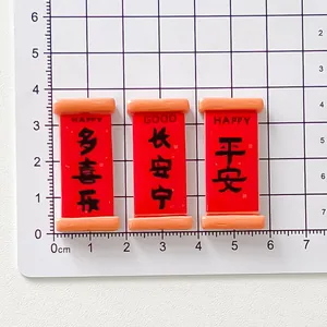 Macro detail of red scroll resin charms on a measurement grid for size reference