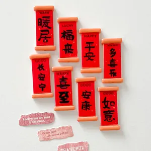 Close-up of miniature red resin scrolls with Chinese blessing characters and English text