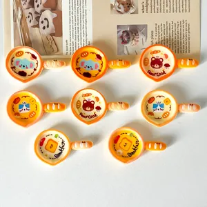 Detailed macro view of cute cartoon frying pan resin charms with cat patterns.