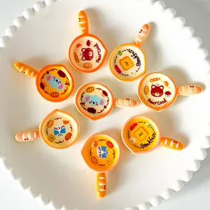 Detail of miniature cartoon cat and bear frying pan resin charms for DIY craft projects