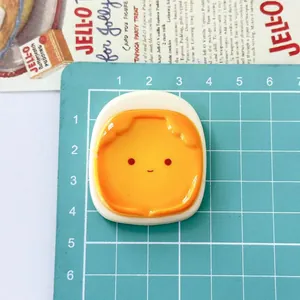 Close-up of a cute large sunny-side-up egg resin charm on a green grid measuring mat