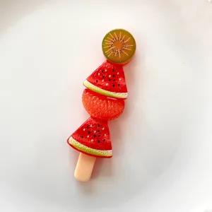 Close-up of a miniature resin fruit skewer featuring kiwi, watermelon, and orange