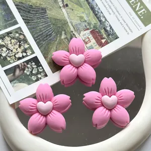 Macro view of pink five-petal resin flower charms with a heart center for DIY crafts.