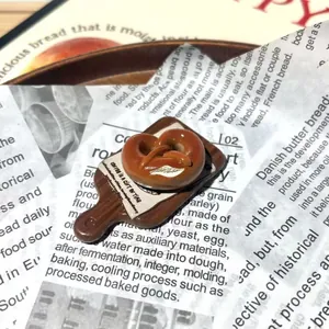 Λεπτομερής άποψη του 3D ρητινούχου μαγνήτη ψυγείου pretzel σε ξύλινη σανίδα