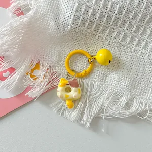 Macro view of a cute calico cat donut keychain with a vibrant yellow bell charm