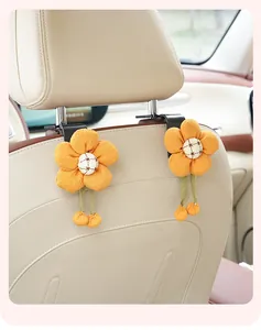 Detail view of cute yellow fabric flower car seat hooks installed on a beige headrest