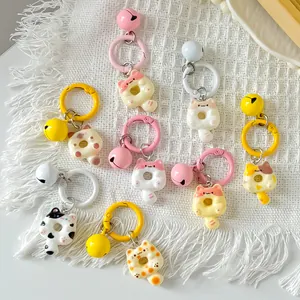 Assorted cute cartoon donut cat keychains with bells on white textured background