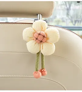 Detail view of a cute plush flower car hook mounted on a beige leather seat back