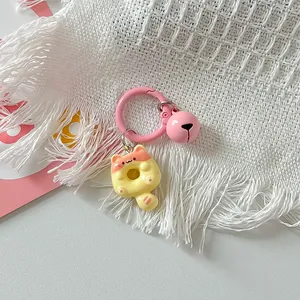 Close-up of a cute cat donut keychain with a pink bell charm and round clip accessory