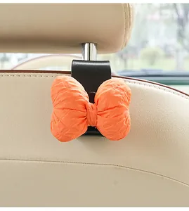 Close-up of a black car headrest hook with a cute orange quilted fabric bow decoration.