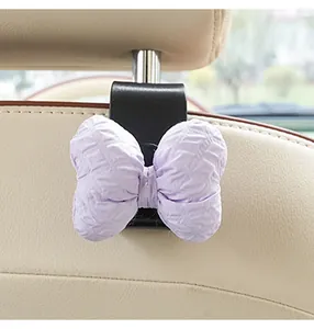 Macro view of a lavender puffy bow car seat back hook mounted on a leather interior