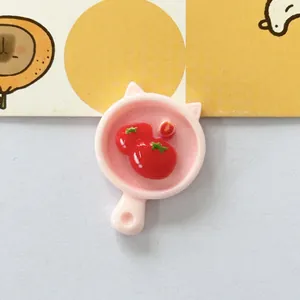 Detaillierte Makroansicht eines süßen rosa Pfannenanhängers aus Harz mit Tomatenmotiven