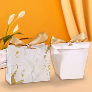 Close-up of elegant marble pattern and plain white gift boxes with golden satin ribbons