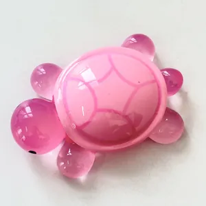 Top view of a pink luminous resin sea turtle ornament on white background