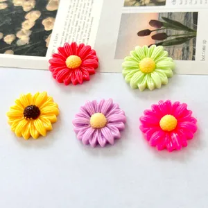 Macro view of five colorful resin daisy flower charms for DIY crafts and hair accessories.