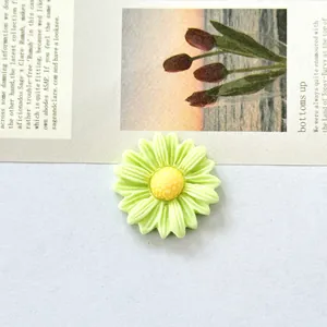 Close-up of light green resin daisy flower charm for DIY crafts and hair accessories