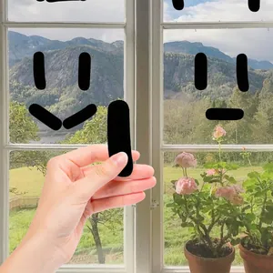 Stickers muraux noirs géométriques en forme de capsule créant des visages sur une fenêtre