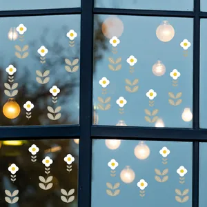 Detalle de pequeñas pegatinas decorativas de flores blancas aplicadas en un cristal de ventana