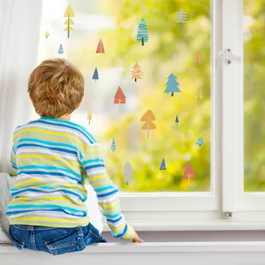 Detailed view of colorful forest tree stickers on a window with a child looking out