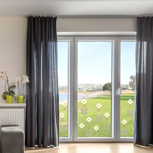 Pequeñas pegatinas de flores blancas en un cristal transparente en una habitación luminosa.