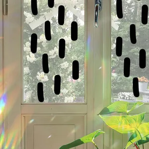 Stickers de fenêtre noirs abstraits sur verre avec vue sur le jardin en arrière-plan.