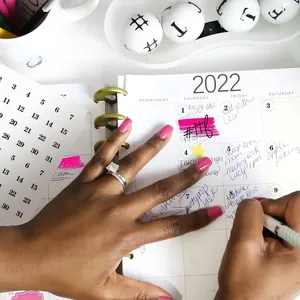 Detailed view of hand applying black number stickers to a white 2022 planner page