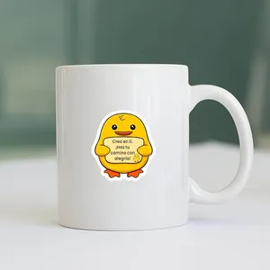 Detailed view of an inspirational Spanish chick sticker applied to a white ceramic mug surface.