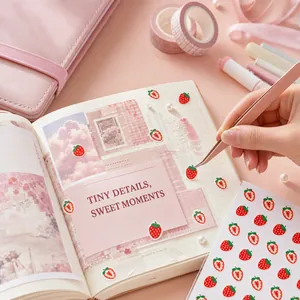 Primer plano de lindas pegatinas de fresas aplicadas en un diario con temática rosa