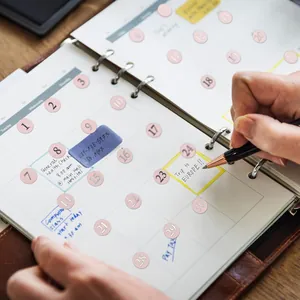 Detail view of pink round date stickers with silver stamping on a monthly planner page