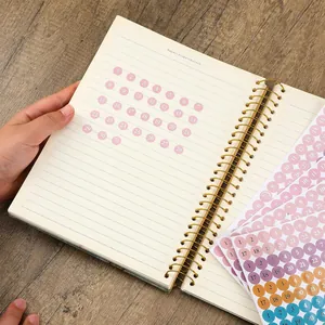 Close-up of colorful round date planner stickers inside a spiral notebook