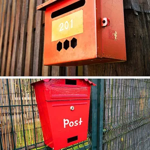 Dettaglio di adesivi bianchi con lettere e numeri applicati su una cassetta postale rossa