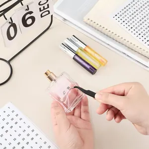 Detail of applying heart and number stickers to a perfume bottle with tweezers