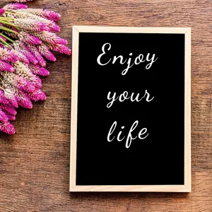 Λευκά αυτοκόλλητα βινυλίου "Enjoy your life" σε μαυροπίνακα με ξύλινο πλαίσιο.