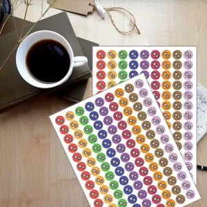 Two sheets of colorful dumbbell fitness planner stickers on a wooden desk with coffee