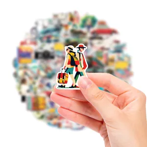 Close-up of a hand holding a colorful travel-themed waterproof sticker for decoration