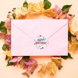 Macro view of 'Happy Birthday' sticker used as a seal on a pink envelope with floral decor