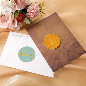 Close-up of round gold foil Happy Birthday sealing stickers on envelopes with flowers.