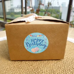 Detail view of a round blue Happy Birthday sticker with colorful balloons on a gift box