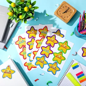 Detailed shot of vibrant star-shaped 'It's My Birthday' stickers on an organized desk setup.