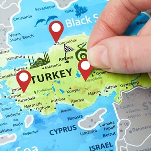 Red map location stickers being applied to a travel map for detailed trip planning