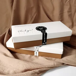 Detalle de pegatinas de agradecimiento blancas y negras en cajas de regalo marrón y blanco