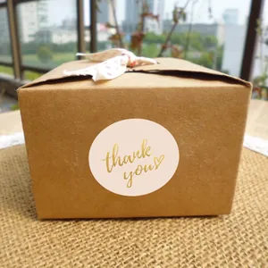 Detailed macro shot of pink 5cm gold foil thank you sticker used as a gift box seal