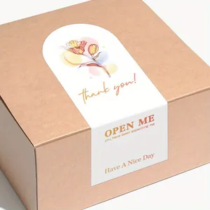 Macro view of floral self-adhesive seal sticker with Thank You text on a kraft gift box