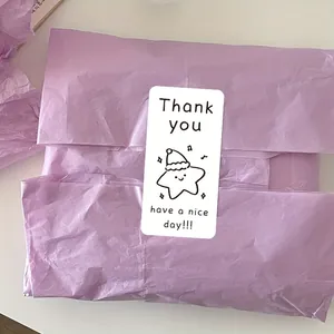 Detail of a cartoon star sticker with 'Thank you' message on purple wrapping paper.