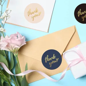 Close-up of 5cm gold foil thank you stickers on paper envelopes and gift packaging